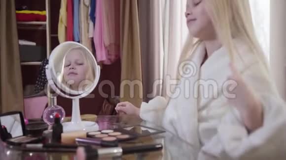 漂亮的白种人小女孩欣赏她在镜子里的倒影可爱的孩子留着白色金色长发的肖像视频的预览图
