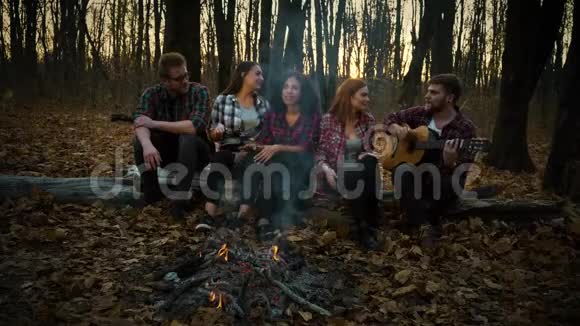 黑暗森林的露营地年轻的游客用吉他唱歌视频的预览图