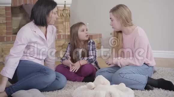 幸福的白种人家庭坐在壁炉前柔软的地毯上交谈的肖像妈妈花时间在视频的预览图
