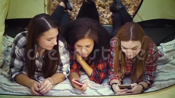 秋林旅游帐篷里使用智能手机的多种族女孩视频的预览图