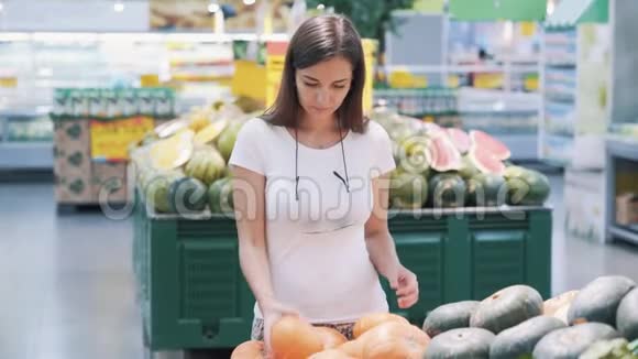 年轻的女游客在超市里选择南瓜闻一闻带走它视频的预览图