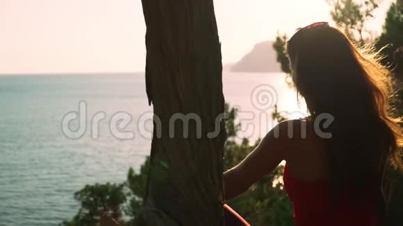 年轻的运动女孩长发坐在美丽的风景大海和日落慢动作对Steadicam的射击视频的预览图
