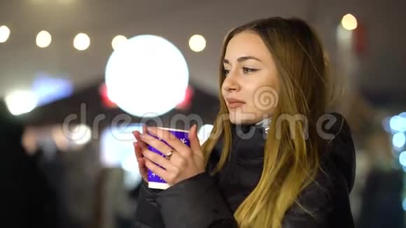 冬天在假日市场上喝热覆盖的葡萄酒的女孩视频的预览图
