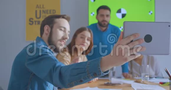 阳光办公室的年轻同事使用平板电脑在线电话会议色度视频的预览图