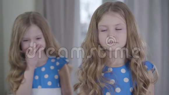 模糊快乐的白种人女孩在严肃的孪生妹妹面前笑着挥手她的脸不同的气质视频的预览图