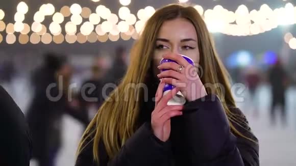 梦中的女孩在冬天的溜冰场附近热饮取暖视频的预览图