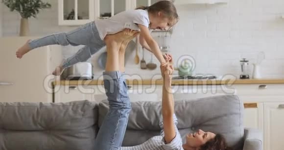 健康的妈妈和小女儿在家练习杂技瑜伽视频的预览图