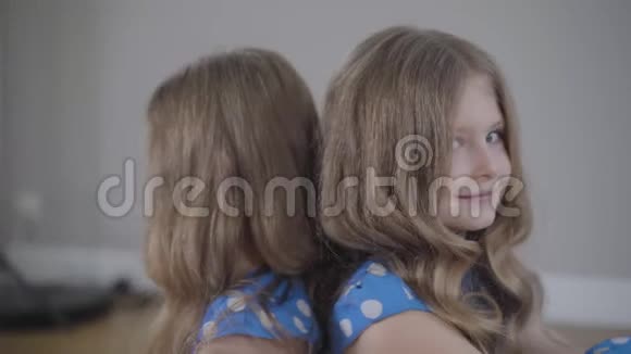 同白种人双胞胎姐妹背靠背坐在室内摄像机从右向左移动两幅肖像视频的预览图