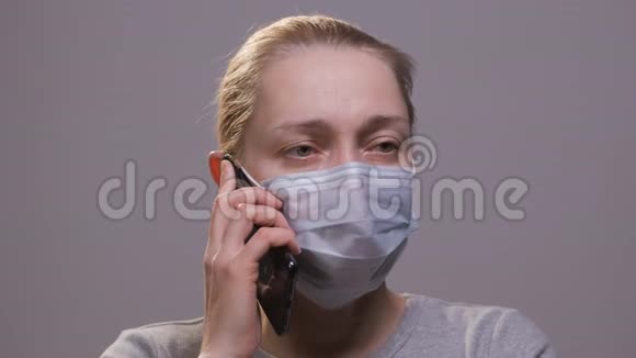 一个戴着医用口罩的女人正在打电话视频的预览图