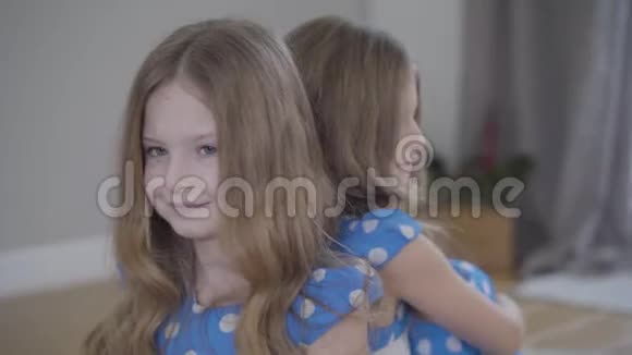 镜头从左到右围绕着两个相同的双胞胎姐妹穿着类似的蓝色虚线连衣裙布鲁内特姐妹视频的预览图