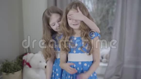 可爱的白种人黑发女孩闭上双胞胎妹妹的眼睛给她打包的礼物感恩的孩子拥抱她可爱的视频的预览图