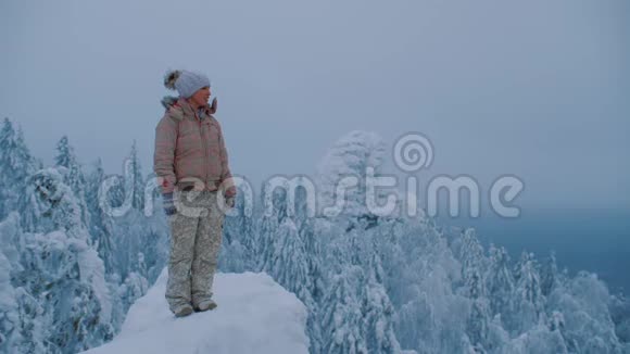 女人站在山顶上享受着奇妙的冬季北方景观视频的预览图