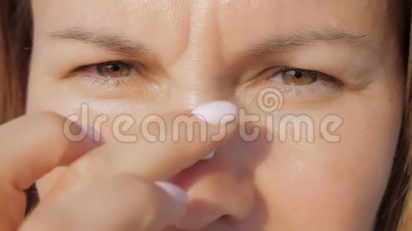 女孩站在沙滩上用防晒霜涂抹她的脸部皮肤视频的预览图