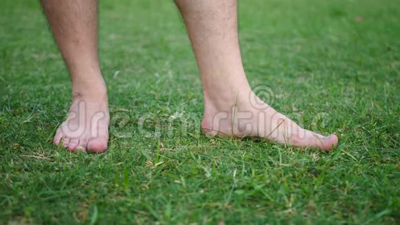 在花园里的鲜切青草上赤脚的雄性脚趾视频的预览图