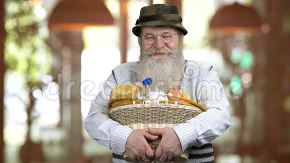 一位退休老人拿着带食物的篮子的肖像视频的预览图