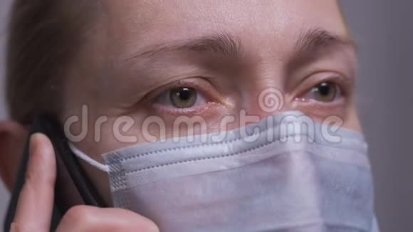 一个戴着医用口罩的女人正在打电话视频的预览图