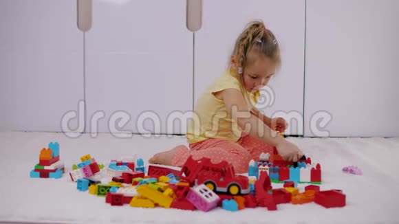 小女孩坐在地毯上玩五颜六色的乐高积木视频的预览图