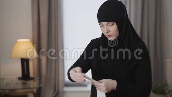年轻的穆斯林妇女戴着传统的头巾举起比尔用震惊的表情看着它青年视频的预览图