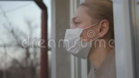 一个戴着医用口罩的妇女从窗口向外看摘下了口罩视频的预览图