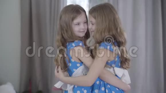 两个快乐的高加索双胞胎姐妹拥抱在室内的肖像头发波浪状眼睛灰色的漂亮黑发女孩视频的预览图