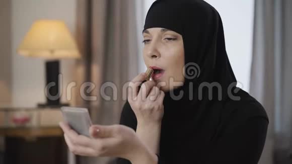年轻美丽的穆斯林女士看镜子和涂口红的肖像现代女性黑人传统头巾视频的预览图