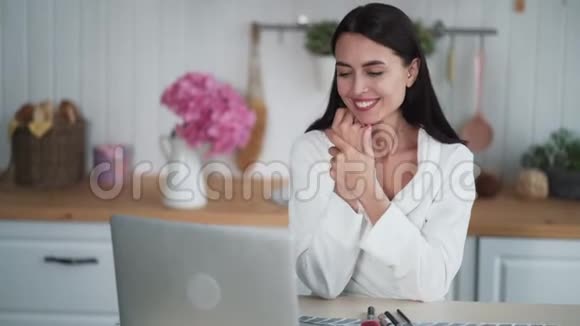年轻女子在笔记本电脑上看电影微笑着享受在家看视频视频的预览图