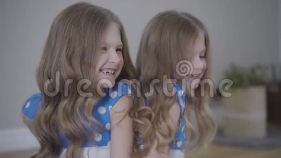 镜头接近两个双胞胎姐妹的脸谈笑风生蓝色点缀着活泼开朗的女孩视频的预览图