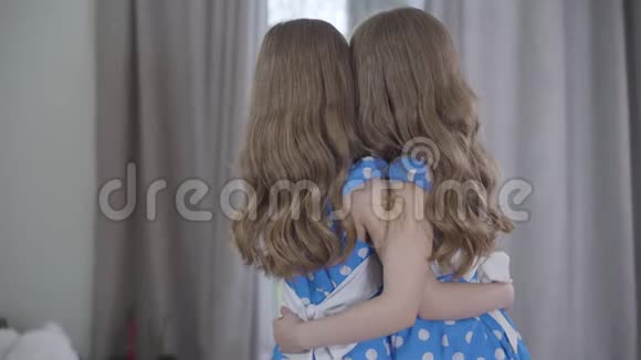 两个棕色皮肤的白种人女孩拥抱并把脸转向相机的背面双胞胎姐妹花时间在一起视频的预览图