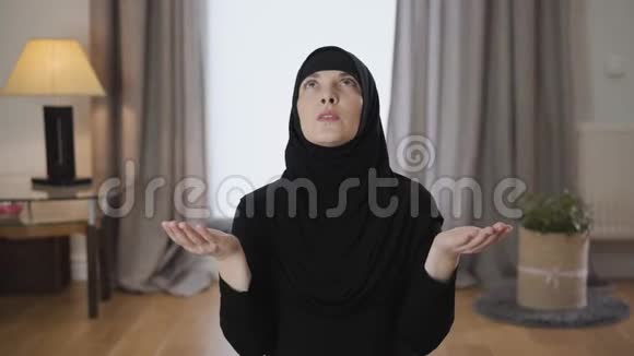 镜头慢慢地接近迷人的穆斯林妇女戴着头巾在家里祈祷传统女性画像视频的预览图