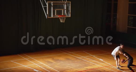 两名篮球运动员卷曲运球夜间比赛对峙进攻防守的俯视图视频的预览图