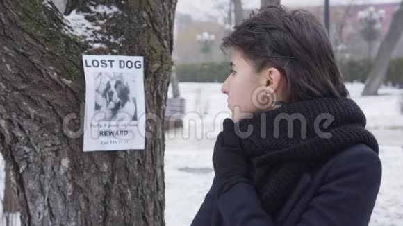 站在冬天的街道上环顾四周的悲伤的高加索女孩的特写肖像关于失犬的公告视频的预览图