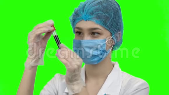 年轻女医生带着口罩看着血试管视频的预览图