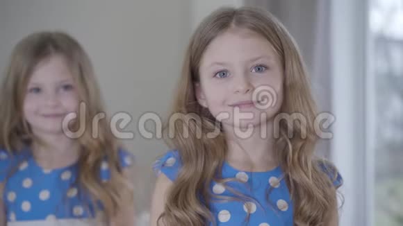 一幅快乐的黑发女孩的肖像灰色的眼睛看着镜头她的孪生妹妹站在背景上视频的预览图
