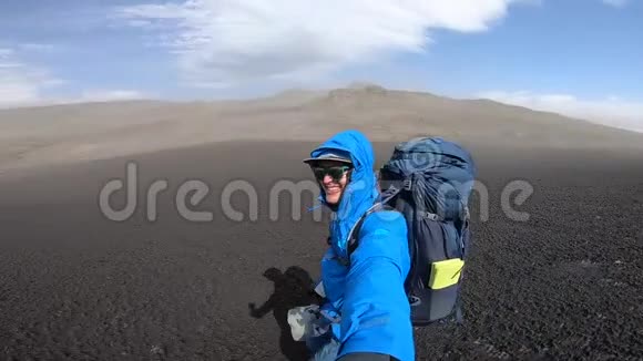 微笑青年男子徒步穿越崎岖的冰岛地形在Fimvorduhals的大风中每秒可达30名拳击手视频的预览图