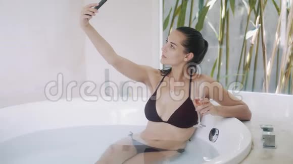带香槟的漂亮女士在浴缸里自拍视频的预览图
