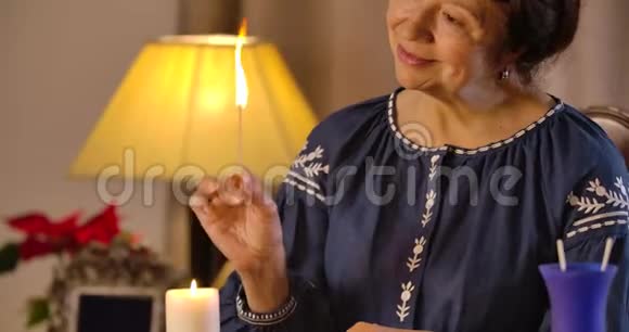 微笑白种人女魔术师用火柴点燃蜡烛镜头上下移动到女人脸上分科视频的预览图