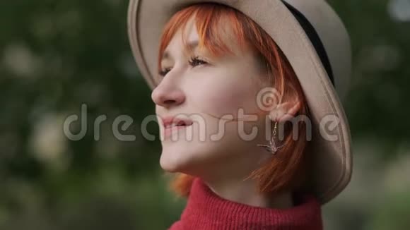 一个年轻迷人的红发女孩一头短发戴着帽子在一个自然公园里穿着一件兵马俑毛衣视频的预览图