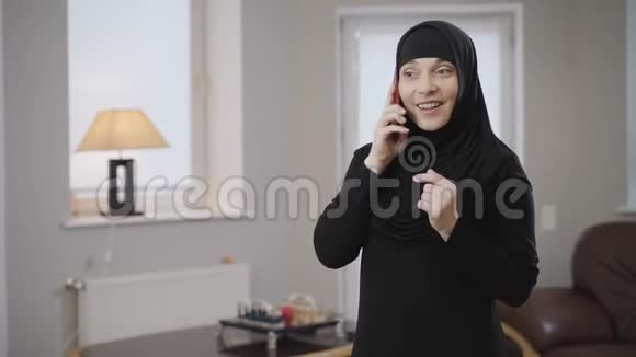 镜头慢慢接近年轻的穆斯林妇女戴着头巾在智能手机上交谈和微笑现代东方女士视频的预览图