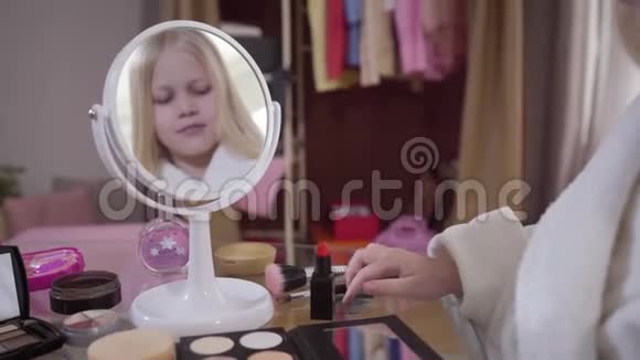 镜子里的小可爱白种人金发女孩带着化妆刷应用眼影年轻时尚视频的预览图