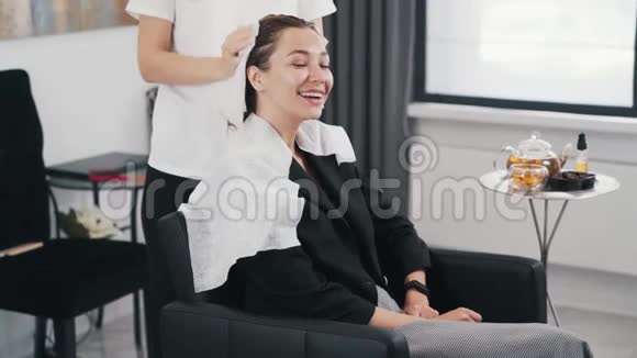 美容师在美容院洗过后用白毛巾擦干女人的头发视频的预览图