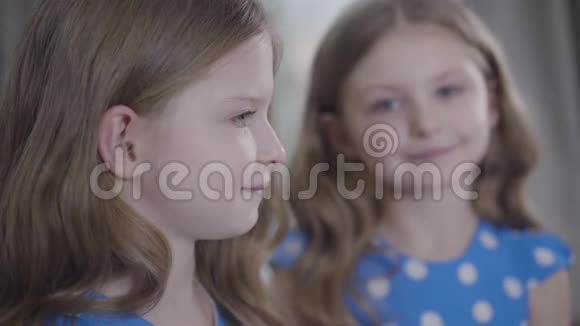一张漂亮的白种人小女孩的肖像背景是她的孪生妹妹模糊的脸两人的特写视频的预览图