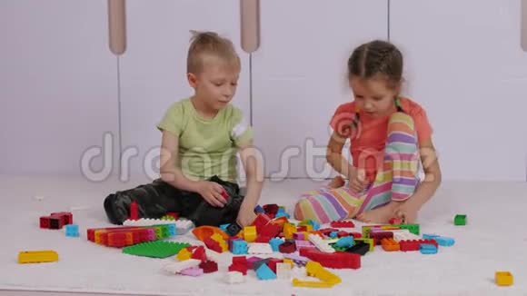 孩子们坐在地毯上玩五颜六色的乐高积木视频的预览图