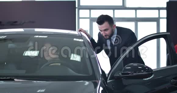 积极英俊的男性经销商咨询成功的女商人坐在司机座位上白种人卖新的视频的预览图