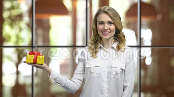 年轻迷人的女人站着右手拿着礼品盒视频的预览图