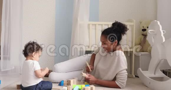 婴儿女儿和妈妈坐在地板上玩木块视频的预览图