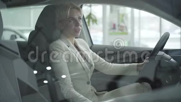 白种人成年女商人穿着优雅的白色西装坐在汽车经销商的座位上的肖像快乐视频的预览图