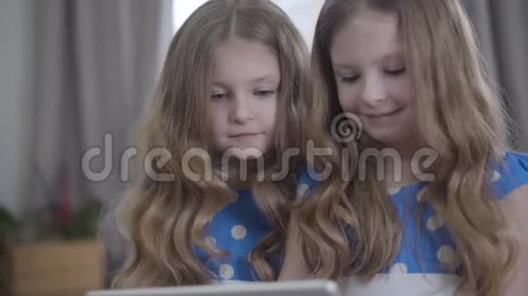 两个漂亮的白人双胞胎姐妹的特写长发卷曲使用平板电脑可爱的黑发女孩的肖像视频的预览图