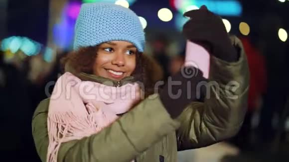 美国黑人女孩晚上在假日市场录制自拍视频视频的预览图