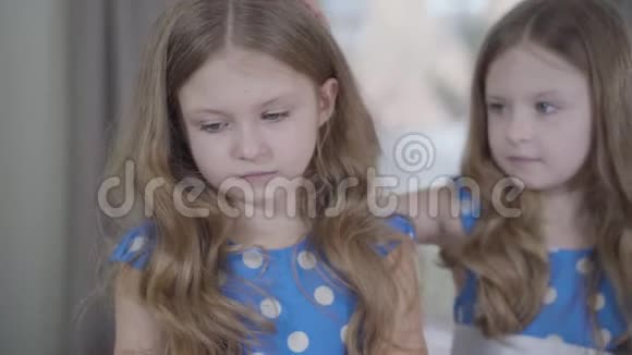 这张照片的特写是一个愤怒的白人小女孩对双胞胎妹妹大喊大叫然后转身回到镜头前冷静的孩子视频的预览图