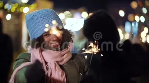 积极的非裔美国女孩在圣诞节市场上玩火花视频的预览图